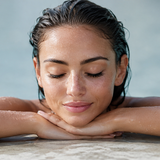 Woman relaxing poolside with wet lashes.