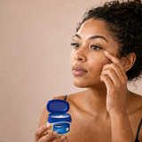 Woman holds Vaseline while tending to eyelashes.