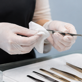 Gloved lash artist sanitising isolation tweezers